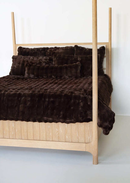 Chocolate Cloud Minky Couture duvet and pillows styled on a wooden canopy bed against a white background.