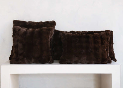 Dark brown Chocolate Cloud Sham faux fur throw pillows arranged on a white shelf.
