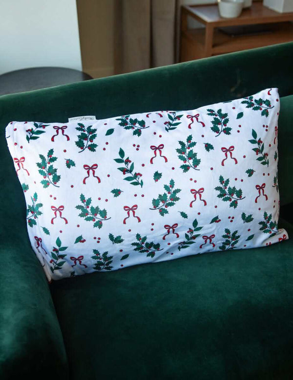 Holly Berries | Christmas Pillowcase featuring festive patterns of holly and bows on a decorative pillow.