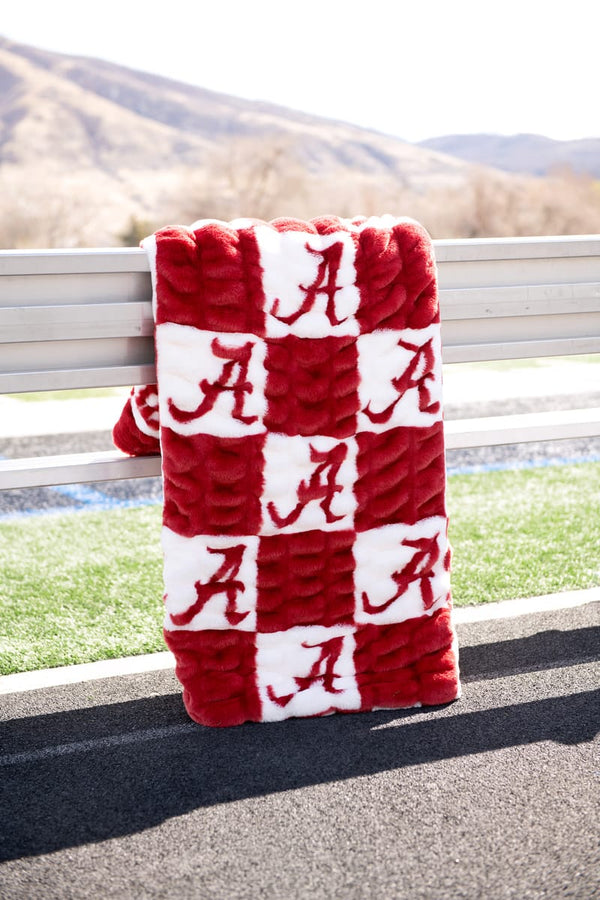 Minky Couture University of Alabama Crimson Tide Blanket displayed on bench with red and white checker pattern.