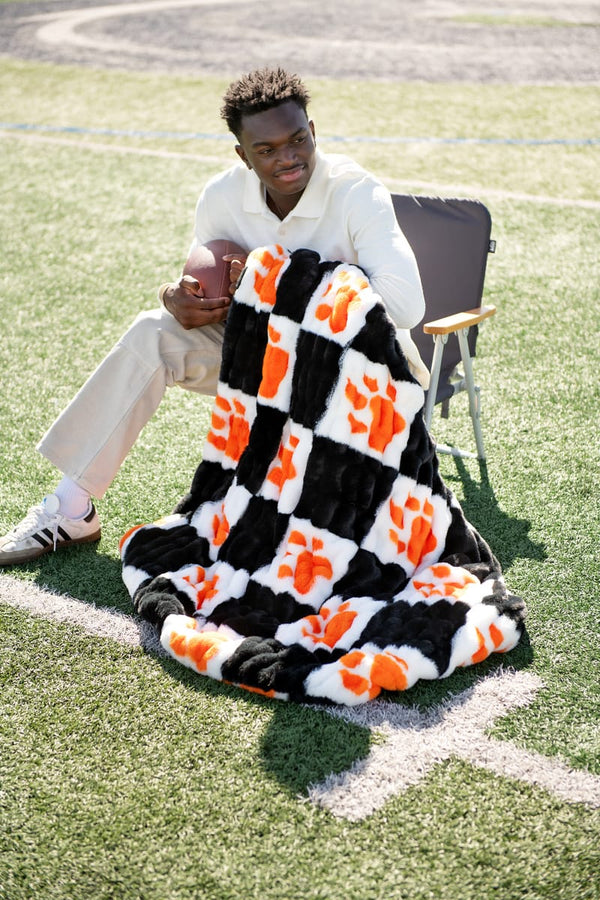 Sam Houston State Bearkats Blanket wrapped around a young man holding a football on a sports field.