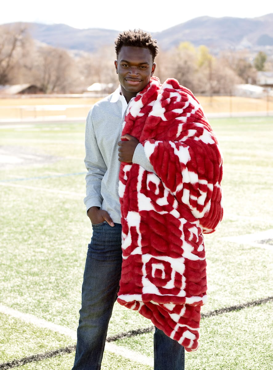 Hugs University of Oklahoma Sooners Blanket draped over a person on a sunny day outdoors.