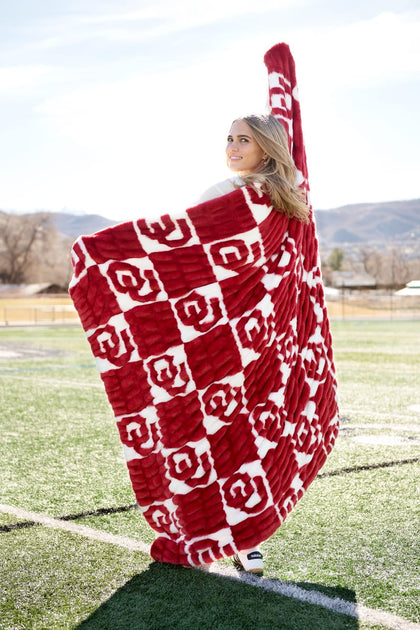 University of Oklahoma Sooners Blanket draped on a woman smiling outdoors on the field.