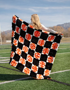 Hugs Idaho State Bengals Blanket displayed on a football field, highlighting its bold checkered pattern.