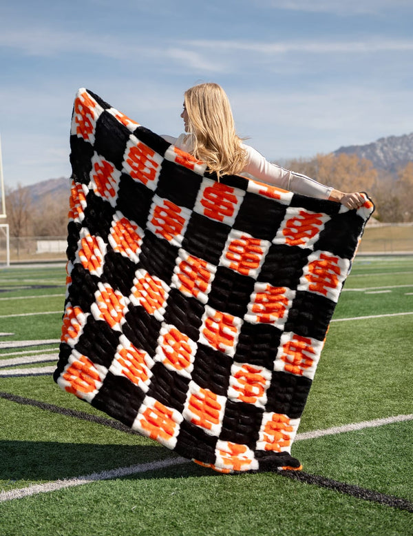 Hugs Idaho State Bengals Blanket displayed on a football field, highlighting its bold checkered pattern.