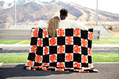 Hugs Idaho State Bengals Blanket used by a couple on a bench showcasing school spirit in bold black and orange.