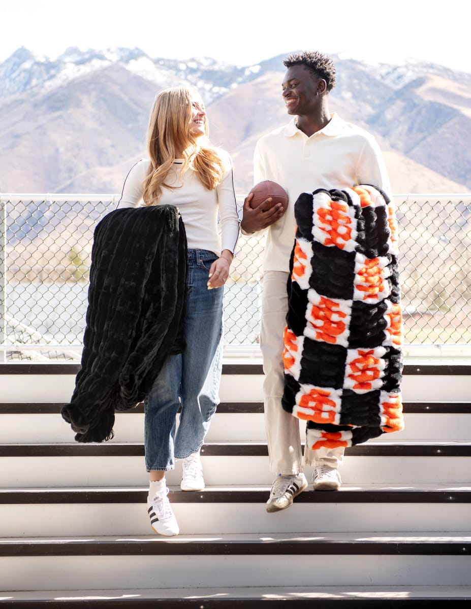 Idaho State Bengals Blanket shown on happy couple outdoors with mountains in background.