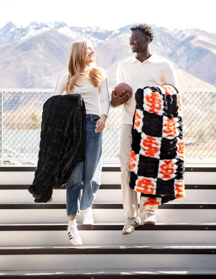 Idaho State Bengals Blanket shown on happy couple outdoors with mountains in background.