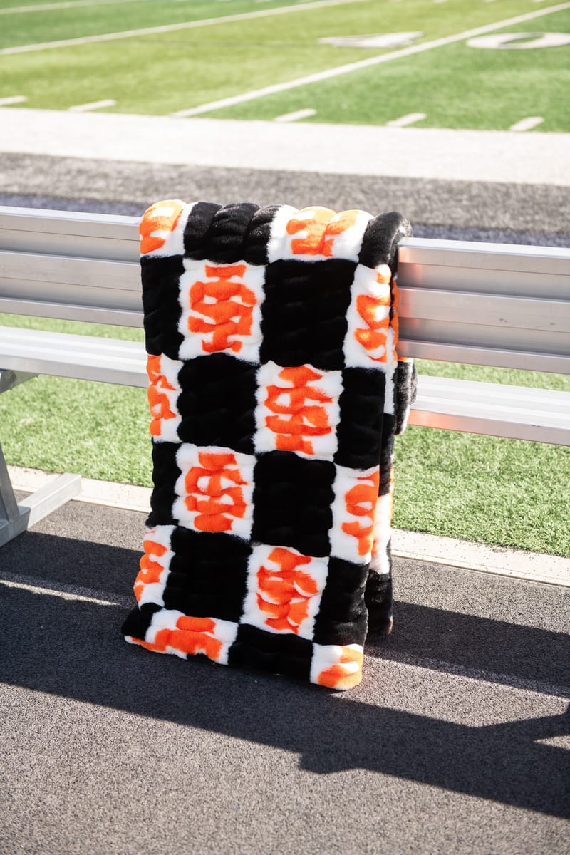 Idaho State Bengals Blanket displayed on a bench with a vibrant black and orange checkered pattern.