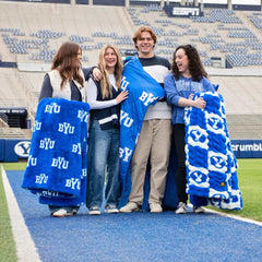 BYU Cougars Blanket displayed by four friends at a football field, showcasing team spirit and cozy comfort.