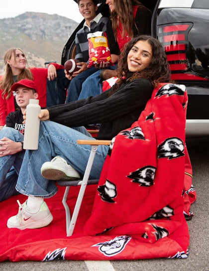 Friends tailgating with Southern Utah Thunderbirds red blanket at truck bed.