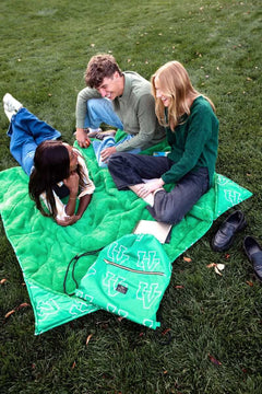 Friends relaxing on a Minky Couture Utah Valley Wolverines green blanket outdoors during a casual campus hangout.