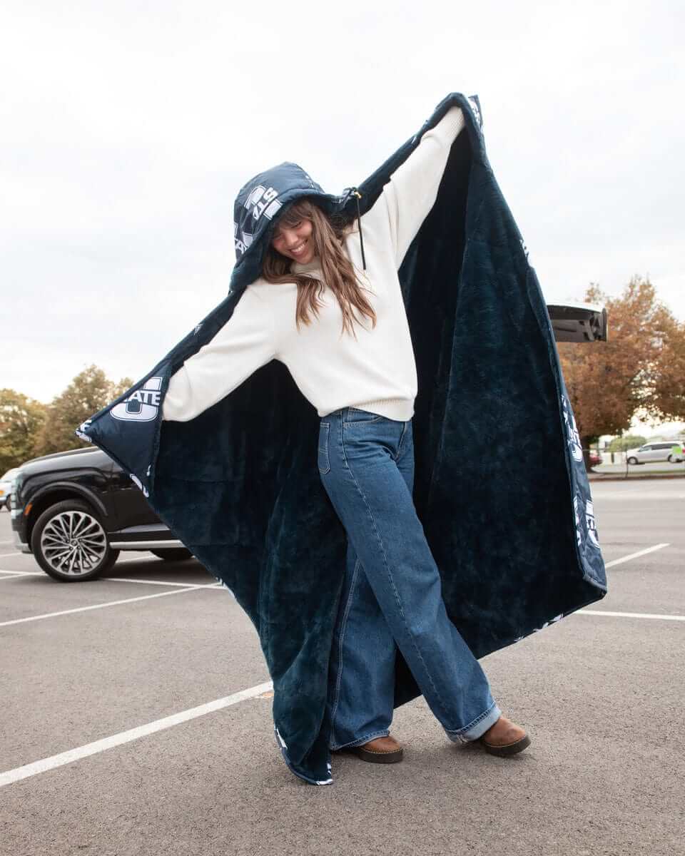 Woman wearing navy Utah State Aggies Minky blanket outdoors in parking lot.