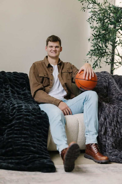 Walker Kessler sitting on a chair with a basketball and black and charcoal Minky weighted blankets.