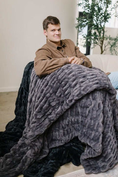 Walker Kessler sitting with a Biggest Hugs Charcoal Blanket draped over his lap.