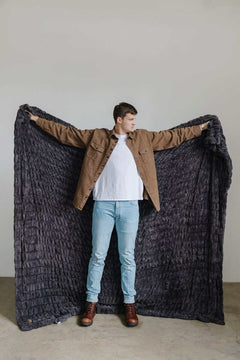 Walker Kessler standing with arms outstretched holding a large charcoal Minky Blanket.