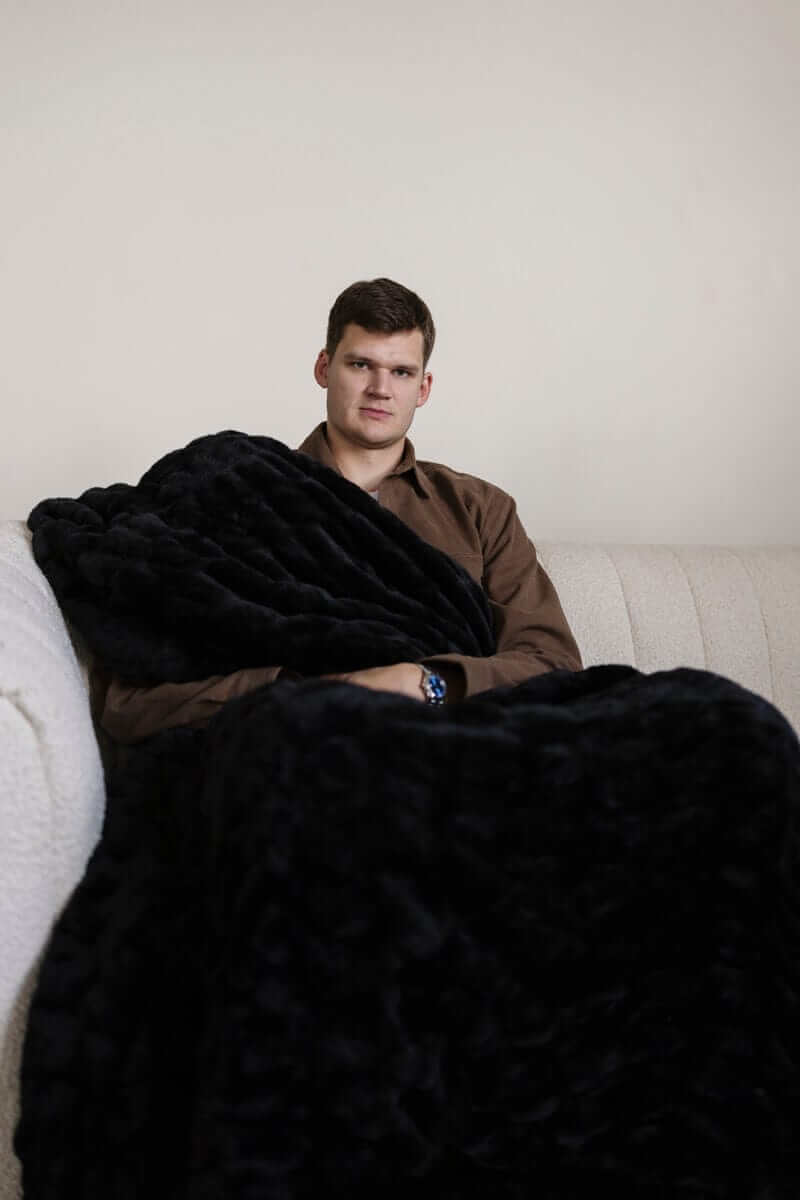 Walker Kessler sitting on a couch wrapped in a large black Minky Blanket.