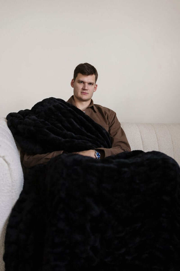 Walker Kessler sitting on a couch wrapped in a large black Minky Blanket.