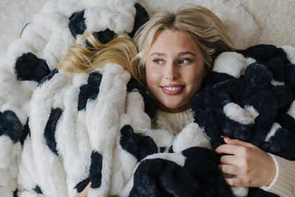 Woman lying down and looking to the side in a black and white Minky polka dots blanket.