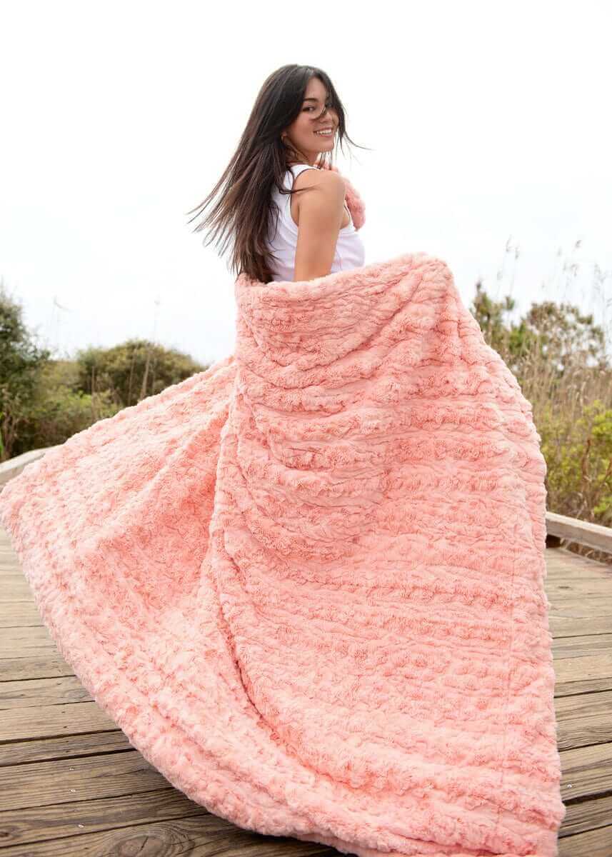 Woman enjoying the Ultra Sorbet Spring Blossom Blanket in a soft pink hue, perfect for cozy relaxation.