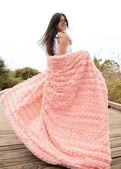 Woman enjoying the Ultra Sorbet Spring Blossom Blanket in a soft pink hue, perfect for cozy relaxation.