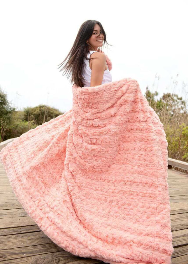 Woman enjoying the Ultra Sorbet Spring Blossom Blanket in a soft pink hue, perfect for cozy relaxation.