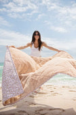 Everywhere Blanket Tan Cheetah being held by a woman on the beach, showcasing the quilted design and prints.