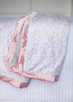 French floral patterned blanket draped over a white bed.