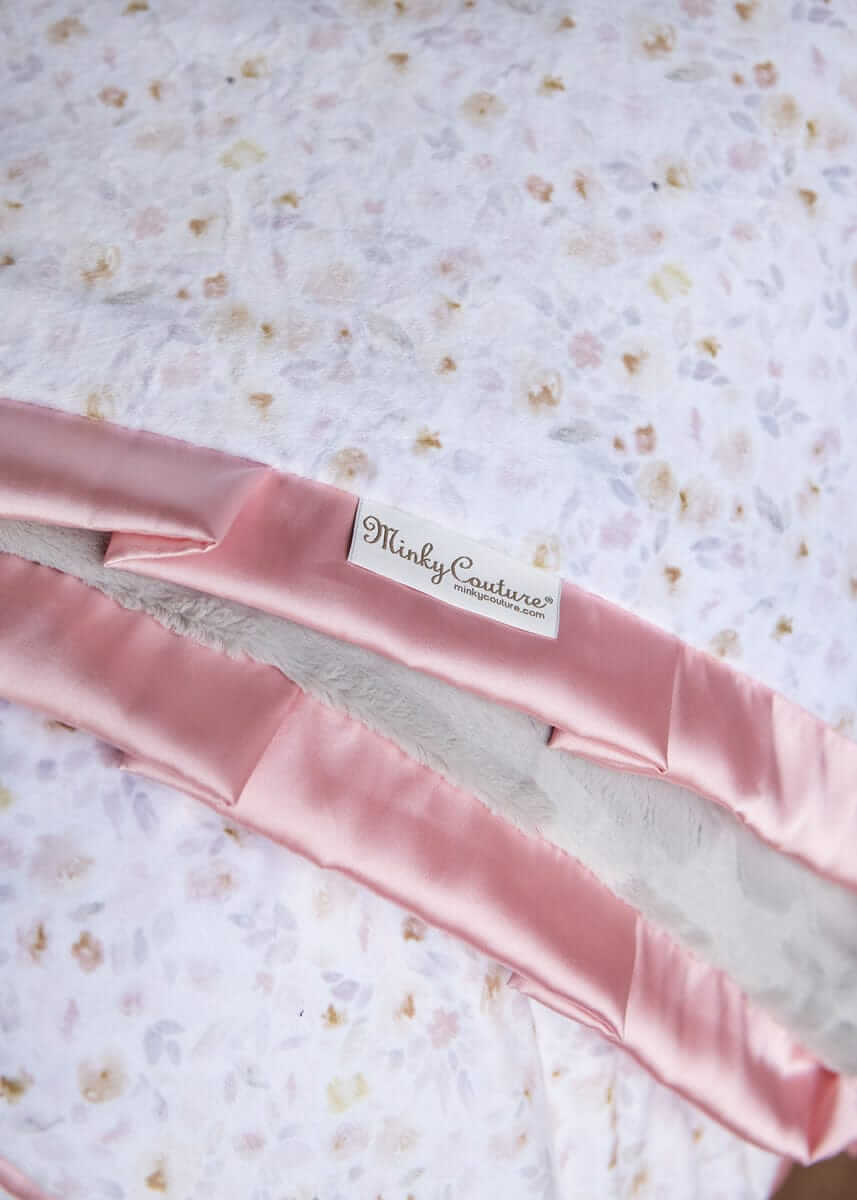Pink satin ribbon with 'Minky Couture' label on a floral fabric background.