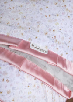Pink satin ribbon with 'Minky Couture' label on a floral fabric background.
