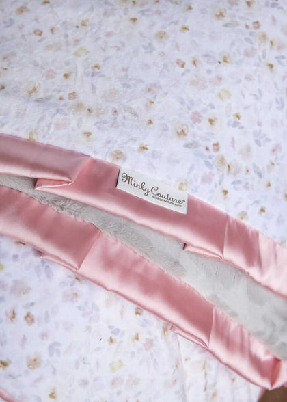 Pink satin ribbon with 'Minky Couture' label on a floral fabric background.