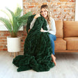 Cozy woman wrapped in the Hugs Pine Blanket, showcasing its plush dark green texture and comfort.