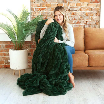 Cozy woman wrapped in the Hugs Pine Blanket, showcasing its plush dark green texture and comfort.
