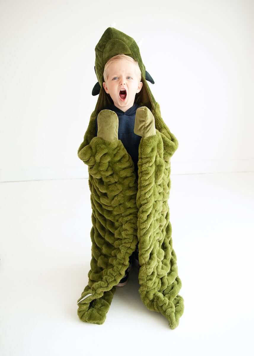 Child wrapped in Minky Couture Huggable Dino green blanket, excitedly embodying a playful dinosaur.