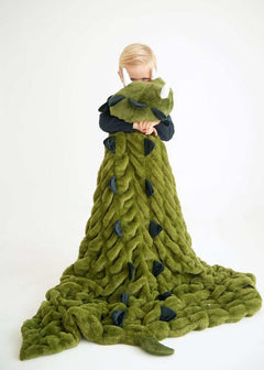 Child wrapped in Huggable Dino green blanket, featuring dinosaur spikes and a cozy design for playful adventures.