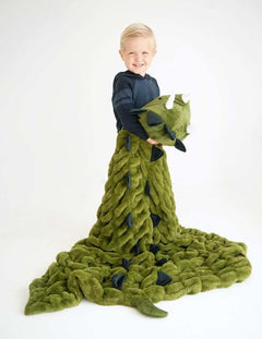 Child smiling while wrapped in Huggable Dino blanket with triceratops head, perfect for imaginative adventures.