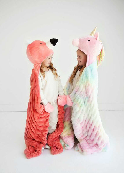 Two children wearing Huggable Unicorn and animal hooded blankets, showcasing colorful designs and cozy comfort.