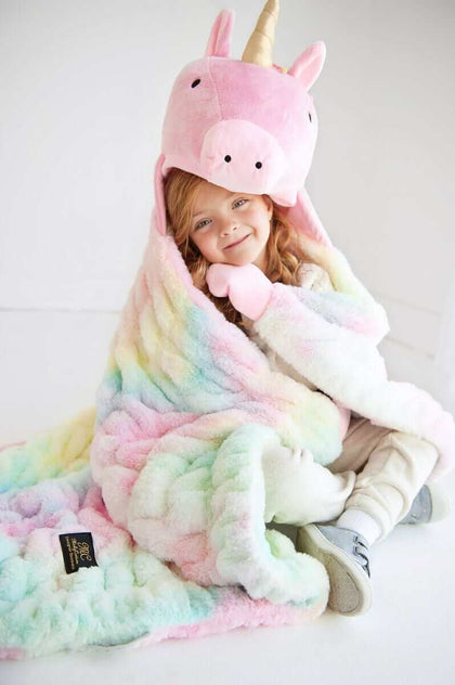 Child snuggled in Huggable Unicorn blanket with unicorn head hood and colorful pastel design.