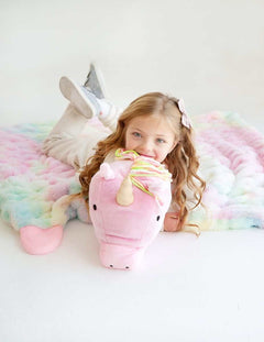 Child cuddling with a Huggable Unicorn blanket featuring a cute unicorn head hood.