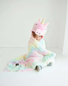 A child wearing the Huggable Unicorn blanket with a unicorn hood, featuring a colorful tie-dye design.