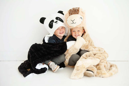 Two kids cuddling with blankets, one is a Huggable Llama, perfect for cozy cuddle sessions.