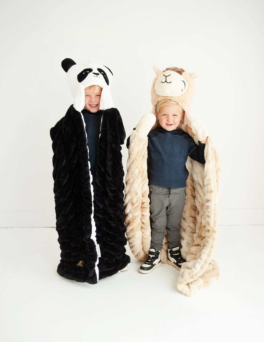 Two children in cozy blankets, one a Huggable Llama and the other a panda, bringing joy and warmth to cuddle time.