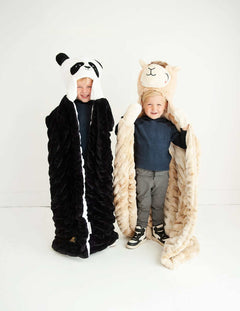 Two children in cozy blankets, one a Huggable Llama and the other a panda, bringing joy and warmth to cuddle time.