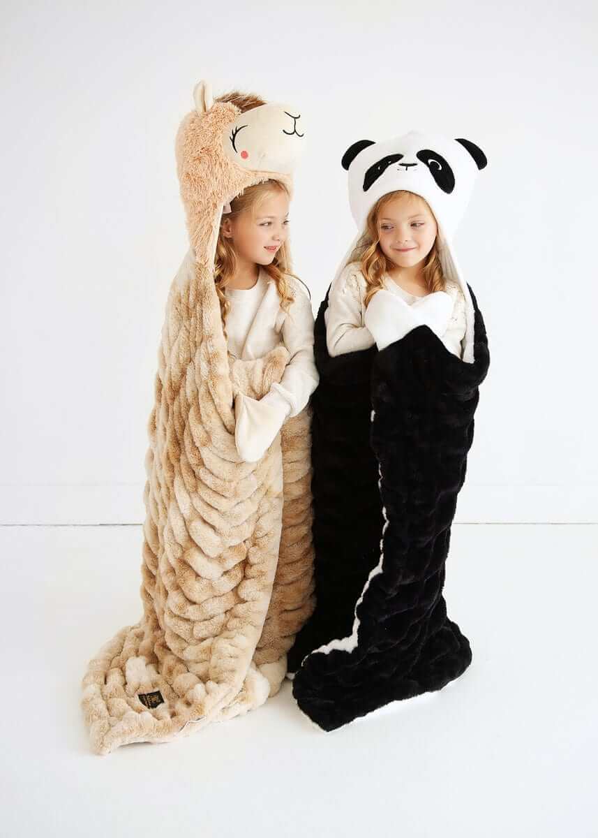 Two kids wrapped in cozy Huggable Llama blankets, one tan llama and one black panda design.