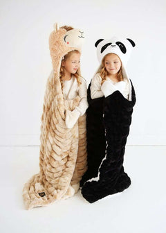 Two kids wrapped in cozy Huggable Llama blankets, one tan llama and one black panda design.