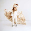 Little girl wearing a Huggable Llama blanket and llama hat, showcasing cozy and fun cuddle time.