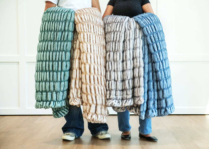 Three individuals showcasing Minky Couture Hugs Blankets, featuring soft faux fur in various stylish colors.