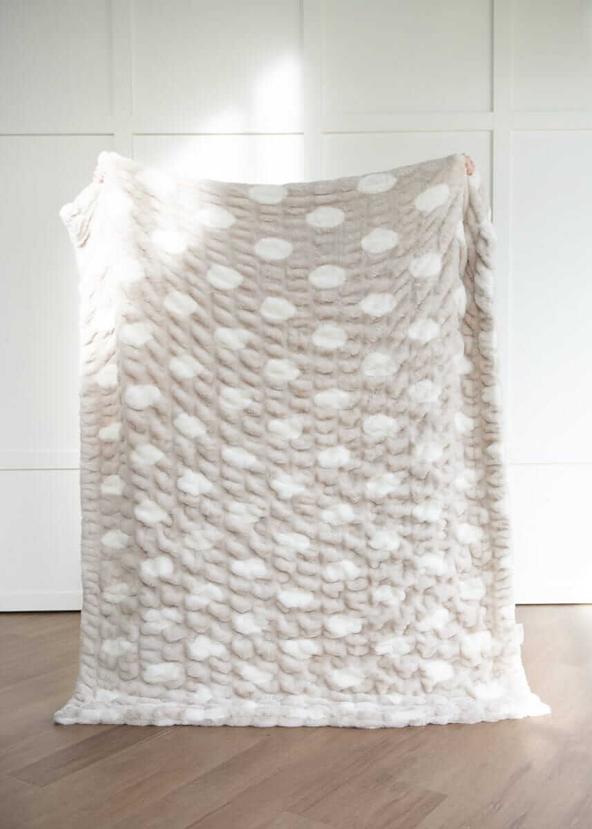Textured Minky Couture blanket with a polka dot pattern draped over a chair against a white wall.
