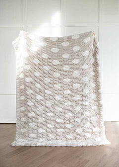 Textured Minky Couture blanket with a polka dot pattern draped over a chair against a white wall.