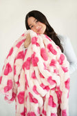 Hugs Heart Pink Blanket being held by a woman, showcasing its plush texture and pink heart pattern.
